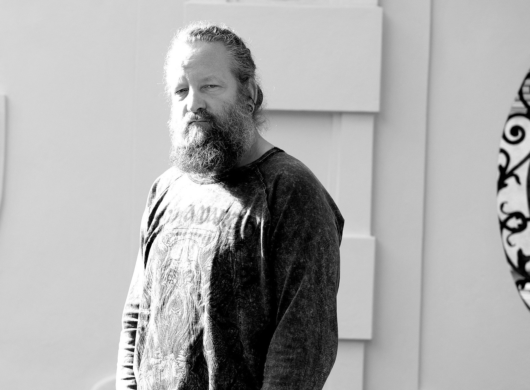 Ein Mann mit Bart vor einer Hausmauer 