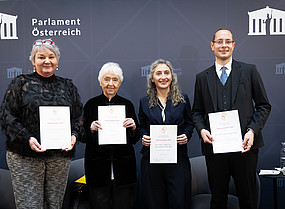 Vier Personen, ein Mann und drei Frauen, halten jeweils eine Urkunde