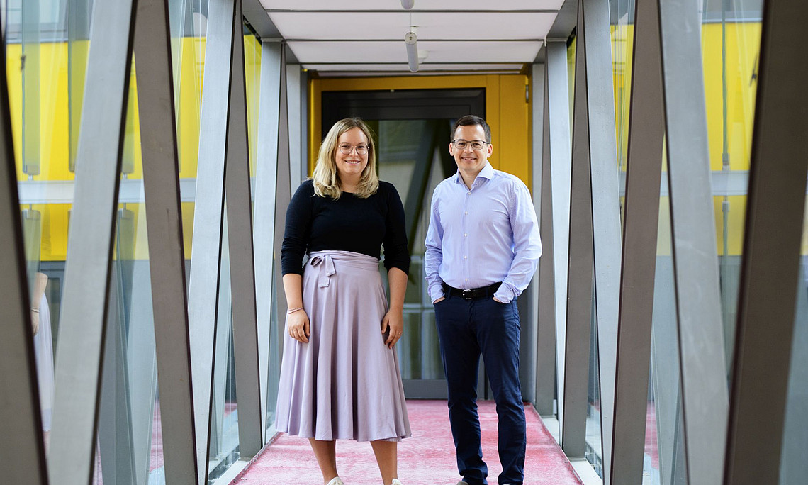 A young woman and a man in a corridor with glass windows