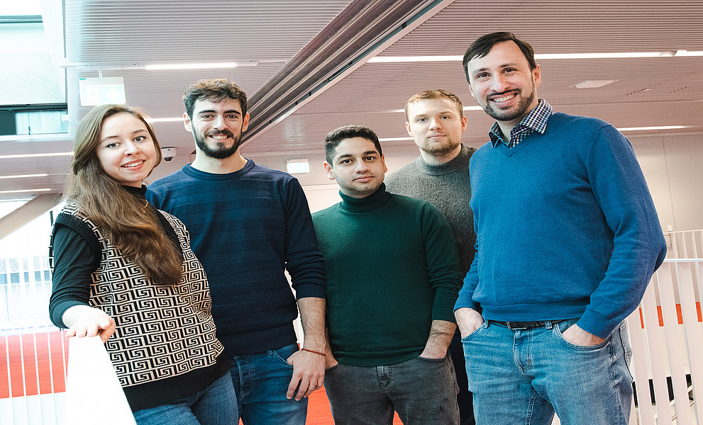 Diana Shakirova, Adrià Conós Valero, Masoud Hamidi, Sergei Gladyshev und Thomas Weiss, stehend in der Universitätsbibliothek