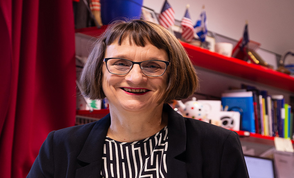 Roberta Maierhofer vor einem Board mit Büchern und ein paar kleinen US-Flaggen
