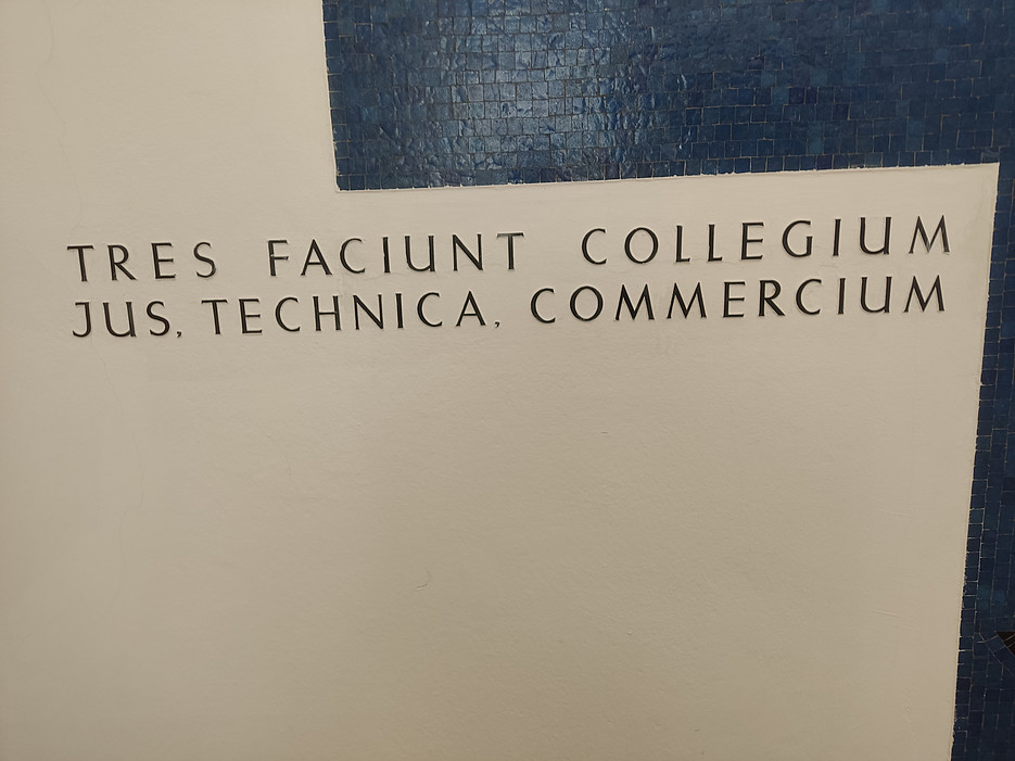Lateinischer Schriftzug auf Wan: "tres faciunt collegium jus, technica, commercium 