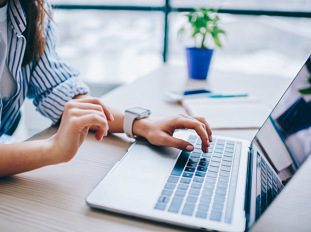 Anmeldung zur Masterprüfung an der SOWI-Fakultät, Eine Frau sitzt an einem Tisch und tippt an einem Notebook. ©BullRun - stock.adobe.com