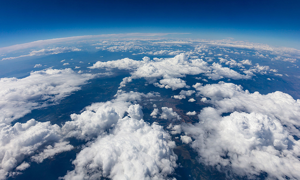 Ausschnitt der Erde von oben, unregelmäßige, weiße Wolkenbänder, blauer Horizont