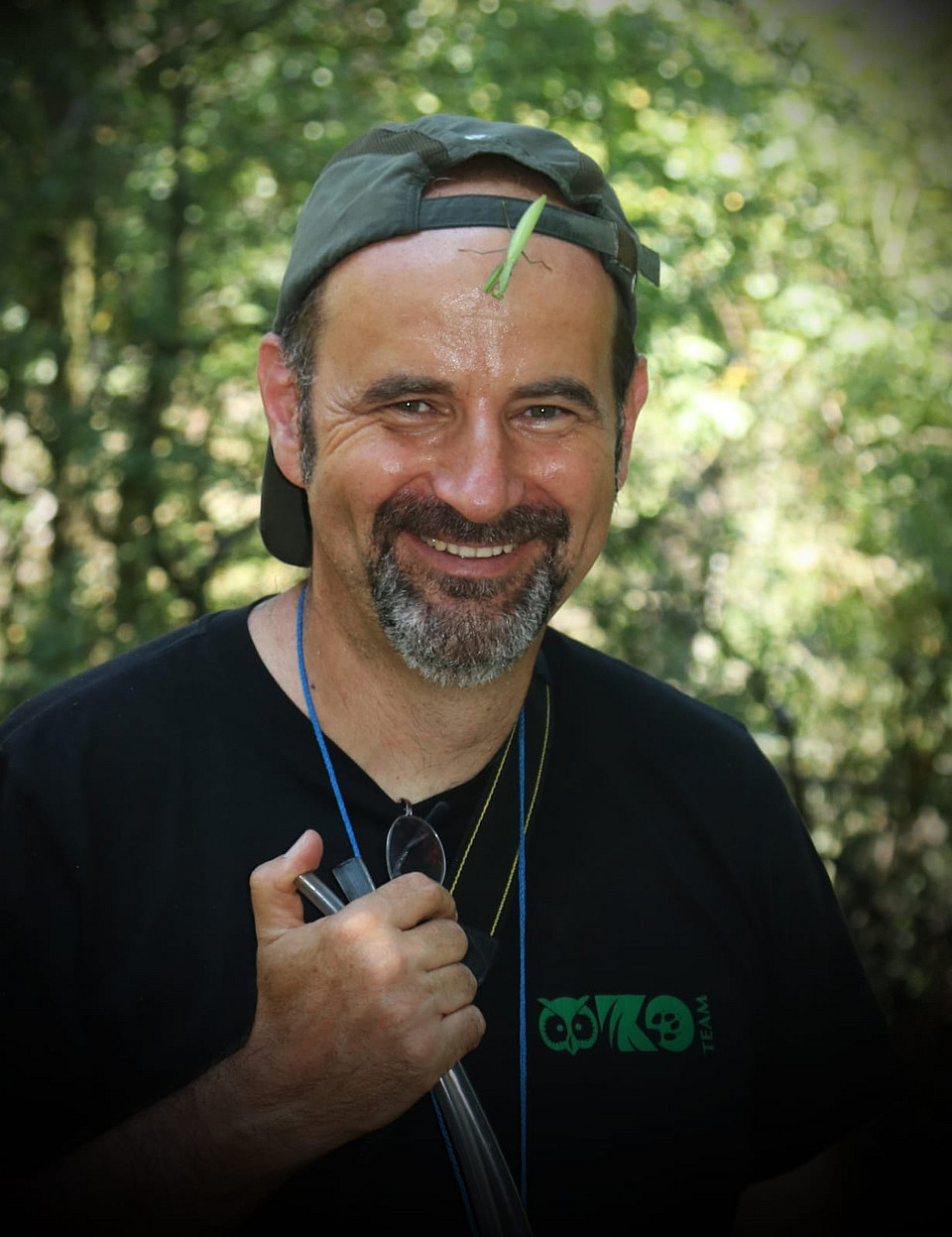Aufnahme von Werner Holzinger, lachend, mit Kappe im Freien; auf seiner Stirn sitzt ein längliches grünes Insekt.