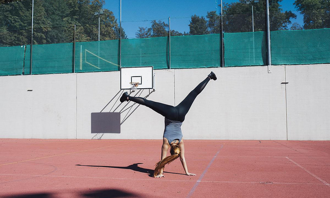 Eine Studierende macht am Basketballplatz der Universität Graz ein Rad.