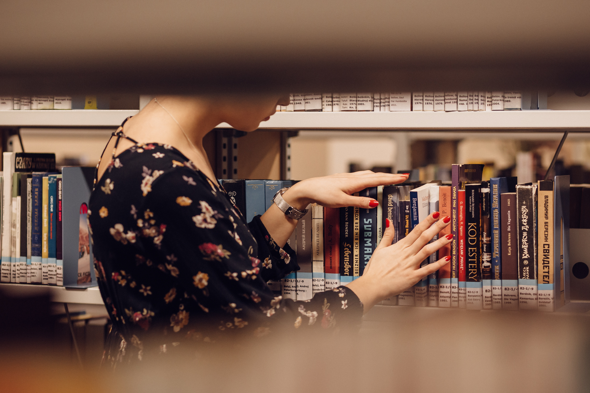 Eine Person durchsucht konzentriert ein Bücherregal in der Bibliothek. 