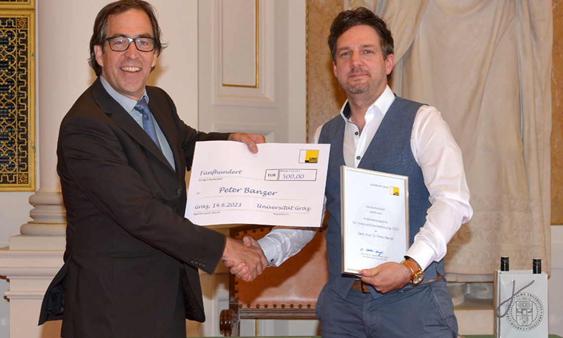 Leonhard Grill überreicht Peter Banzer den Anerkennungspreis in der Höhe von EUR 500. Foto: Uni Graz / Pichler