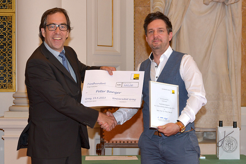 Leonhard Grill überreicht Peter Banzer den Anerkennungspreis in der Höhe von EUR 500. Foto: Uni Graz / Pichler