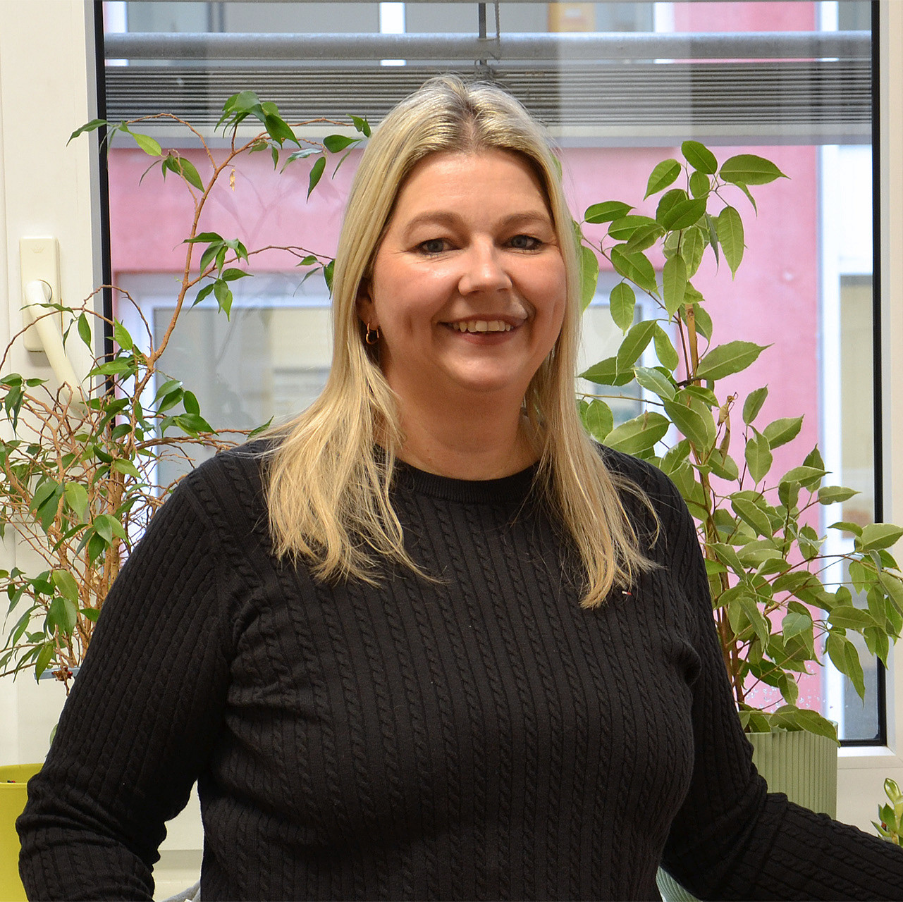 Portrait einer Frau mit langen blonden Haaren in einem schwarzen Pullover