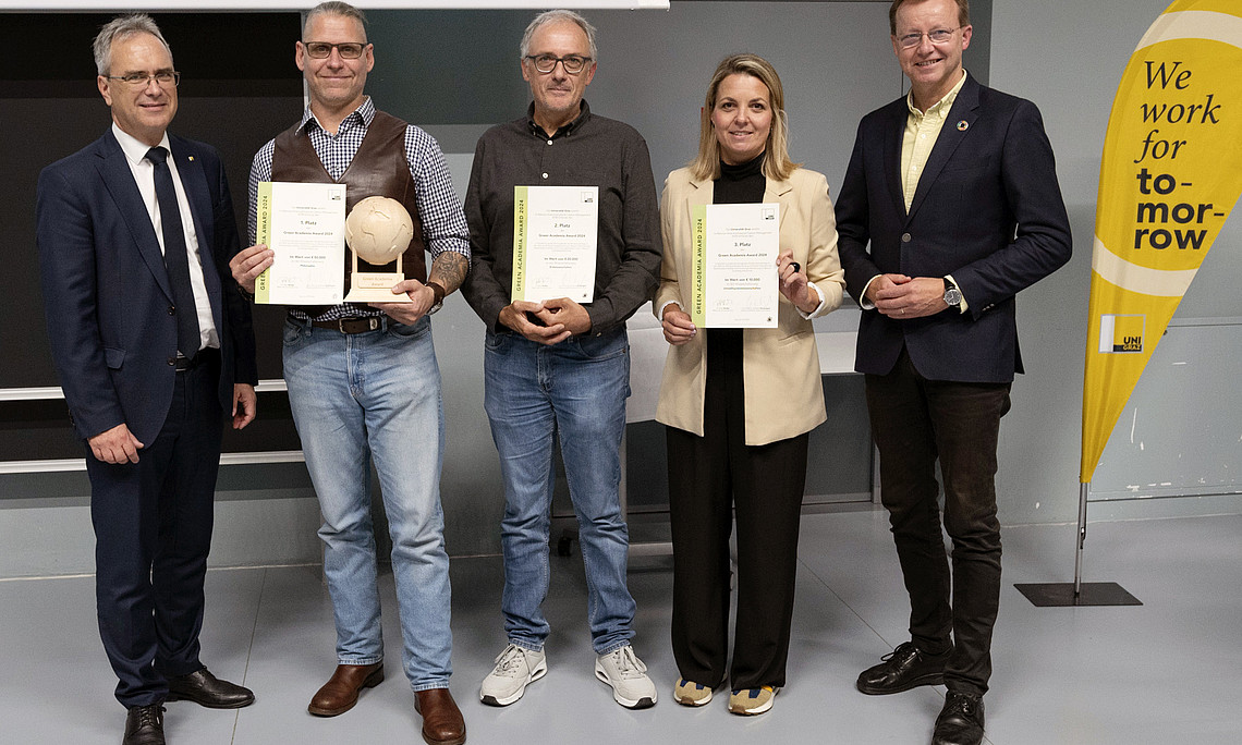 Rektor Peter Riedler, Harald Stelzer, Walter Kurz, Romana Rauter und Gottfried Kirchengast bei der Verleihung des Green Academia Award mit Urkunden, Trophäe und Uni-Graz-Beachflag mit der Aufschrift „we work for tomorrow“