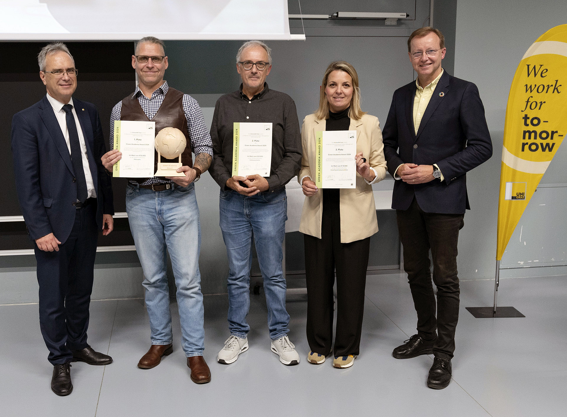Rector Peter Riedler, Harald Stelzer, Walter Kurz, Romana Rauter and Gottfried Kirchengast at the presentation of the Green Academia Award with certificates, trophy and Uni Graz beach flag with the inscription "we work for tomorrow" ©Uni Graz/Angele