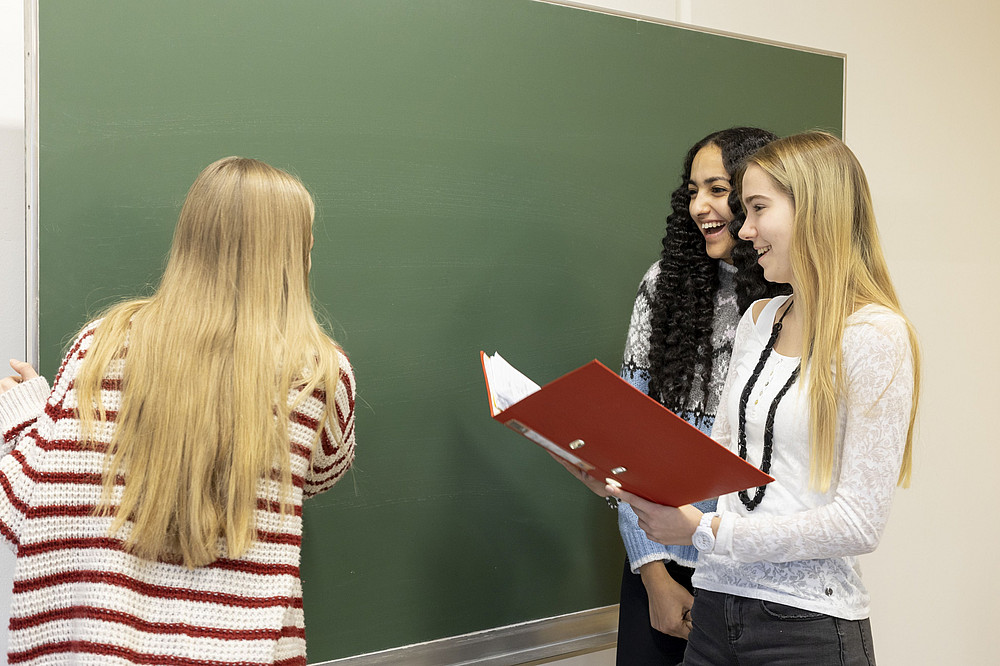 Leere Tafel, 3 lächelnde Schülerinnen ©FDZ