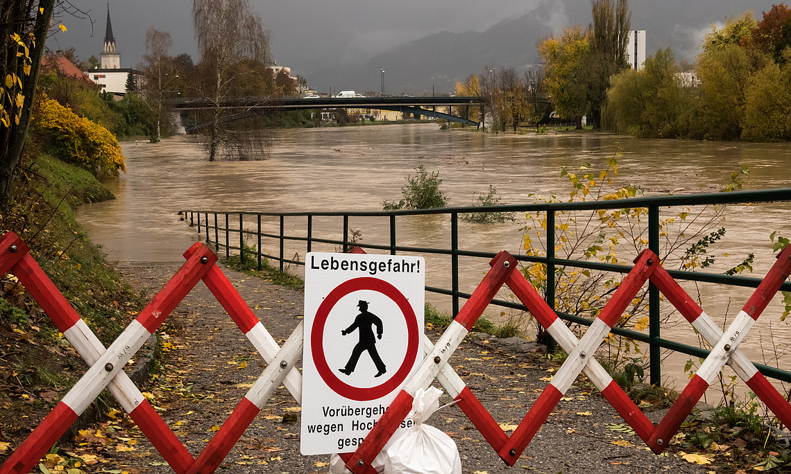 Ein Schild mit der Aufschrift „Lebensgefahr“ wird während des Herbsthochwassers vor einem rot-weiß gestreiften Eisenzaun am überfluteten Fluss Drau in Villach, Österreich, auf den Boden gelegt. 