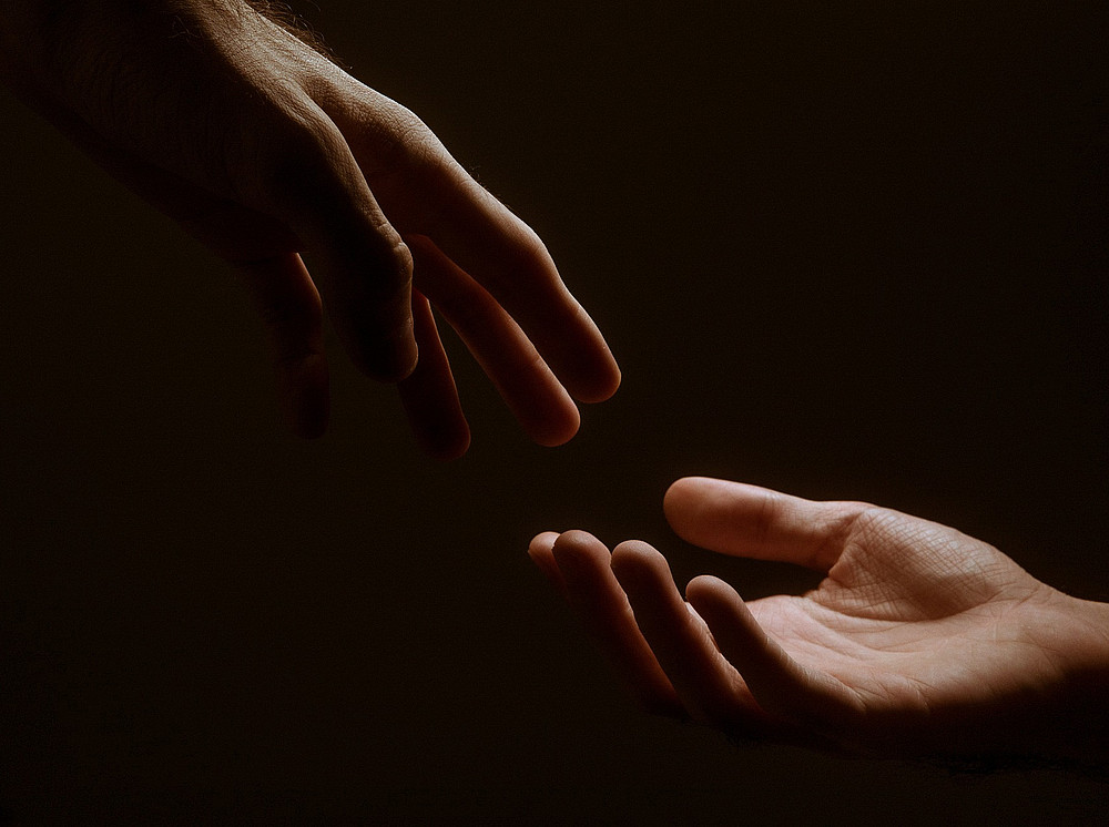 Zwei Hände, die im Dunkeln nacheinander greifen ©Jackson David