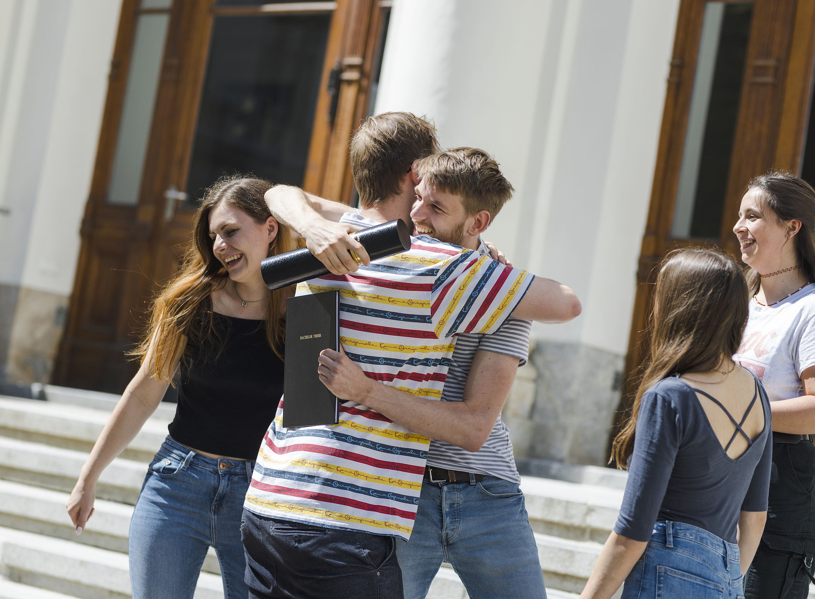 Studierende umarmen sich vor dem Hauptgebäude der Uni Graz ©Uni Graz/Kanizaj