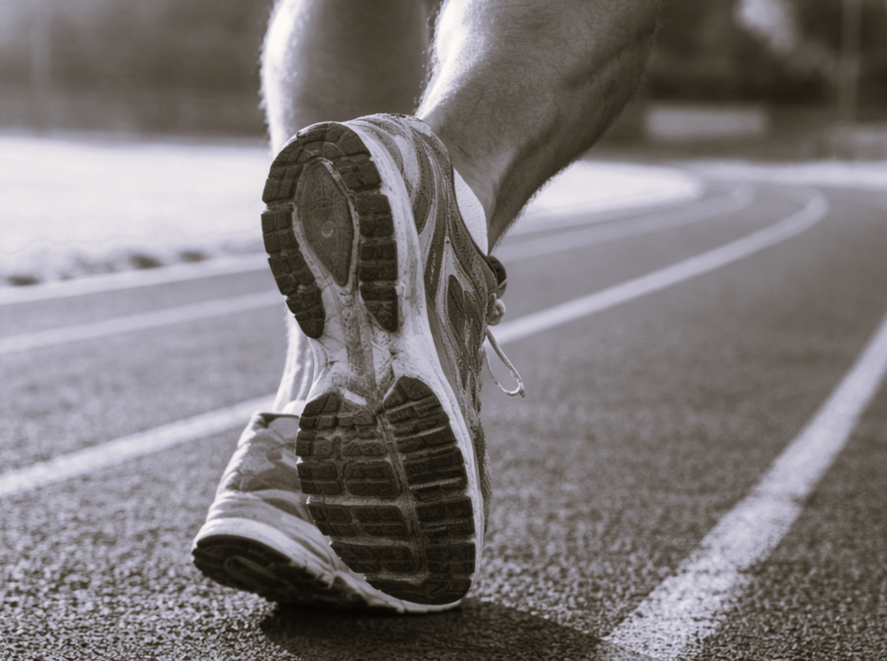 Nahaufnahme eines männlichen Fußes mit Laufschuhen auf einer Sportbahn 