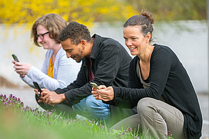 drei Personen in der Natur, die mit dem Handy fotografieren