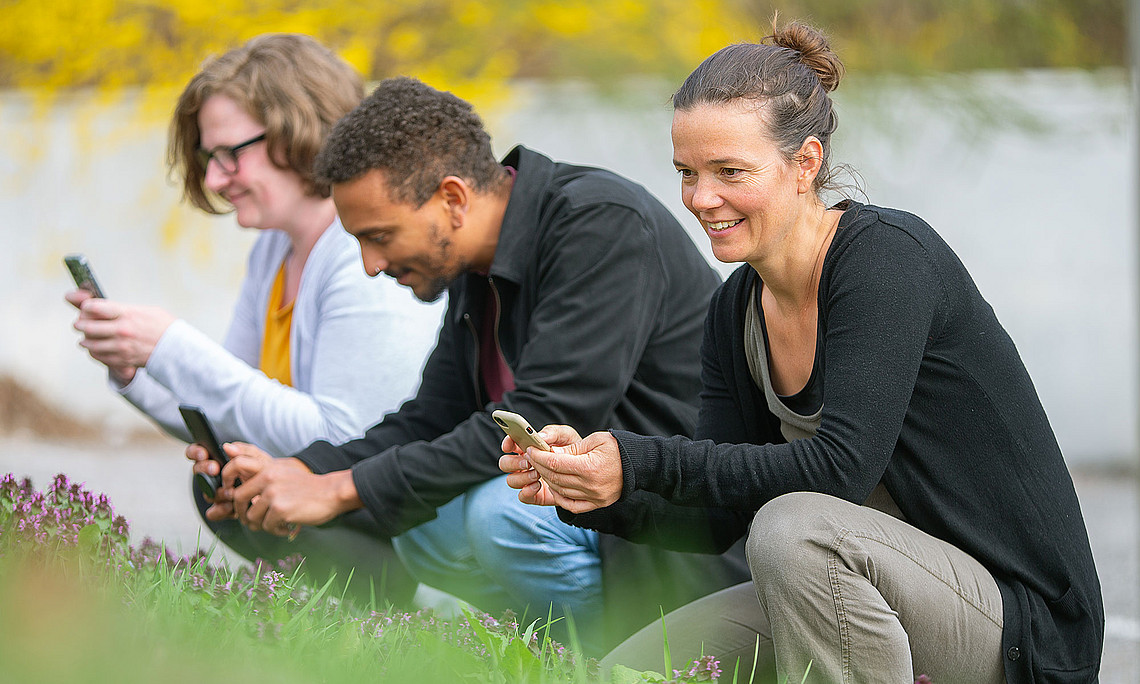 drei Personen in der Natur, die mit dem Handy fotografieren