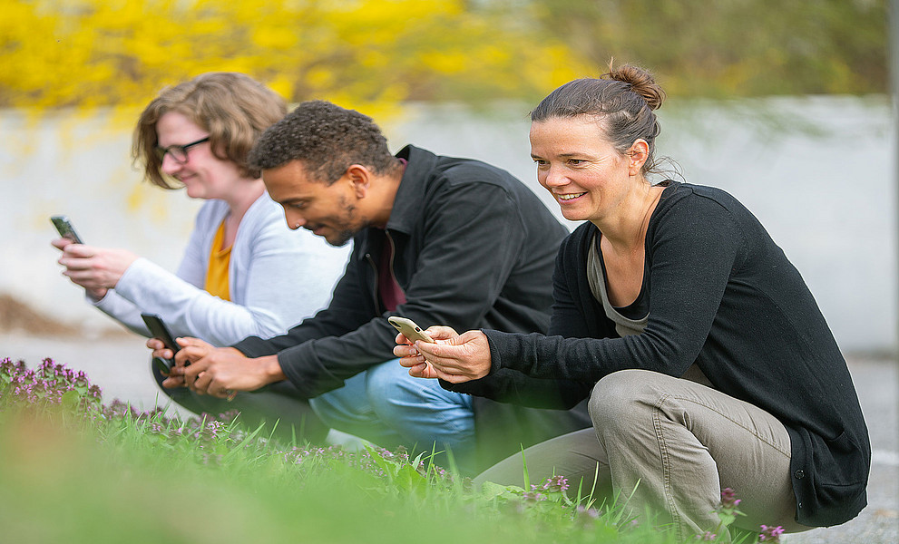 drei Personen in der Natur, die mit dem Handy fotografieren