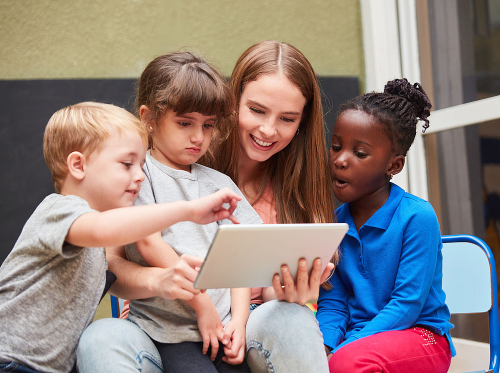 Young woman sits in front of a tablet with children and symbolizes the SAID project ©Robert Kneschke - stock.adobe.com