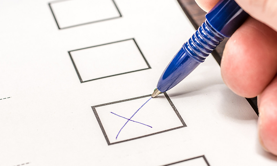 Detail of hand with pen making a cross on a ballot paper.