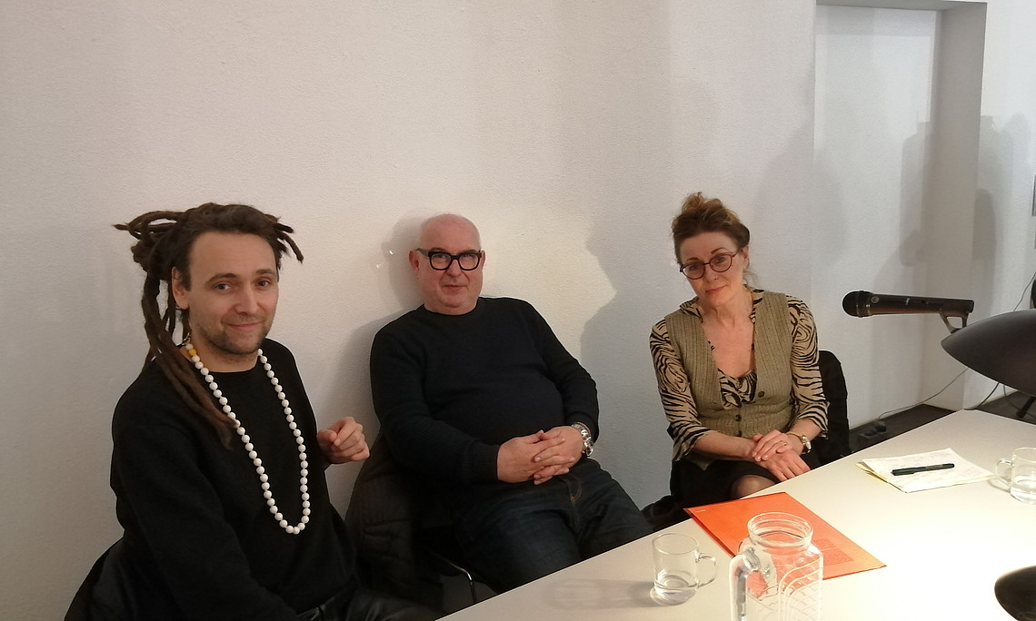 3 Personen sitzen an einem Tisch