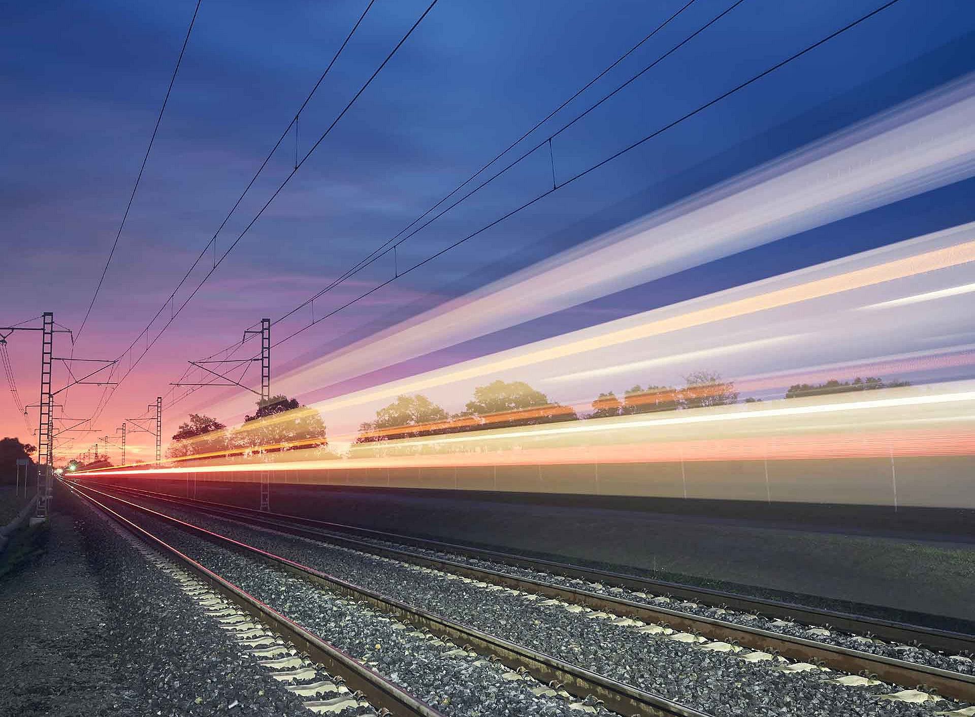 Bahngleise am Abend mit bunten Lichtstreifen 