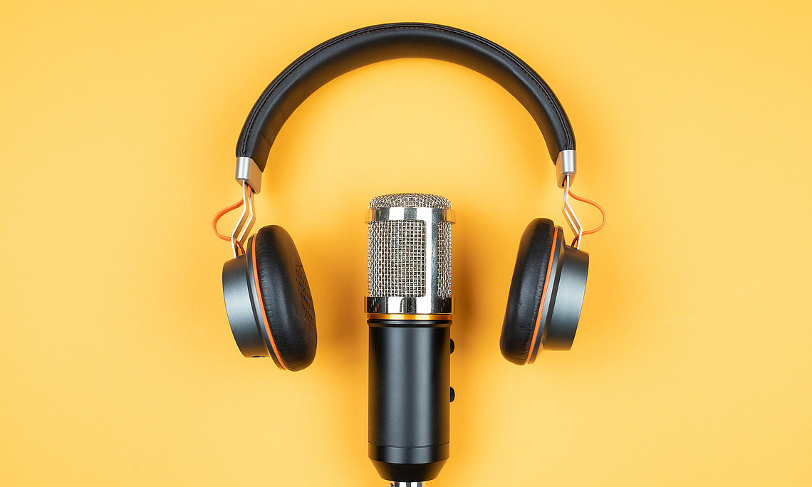 podcasting concept, directly above view of headphones and recording microphone on orange background