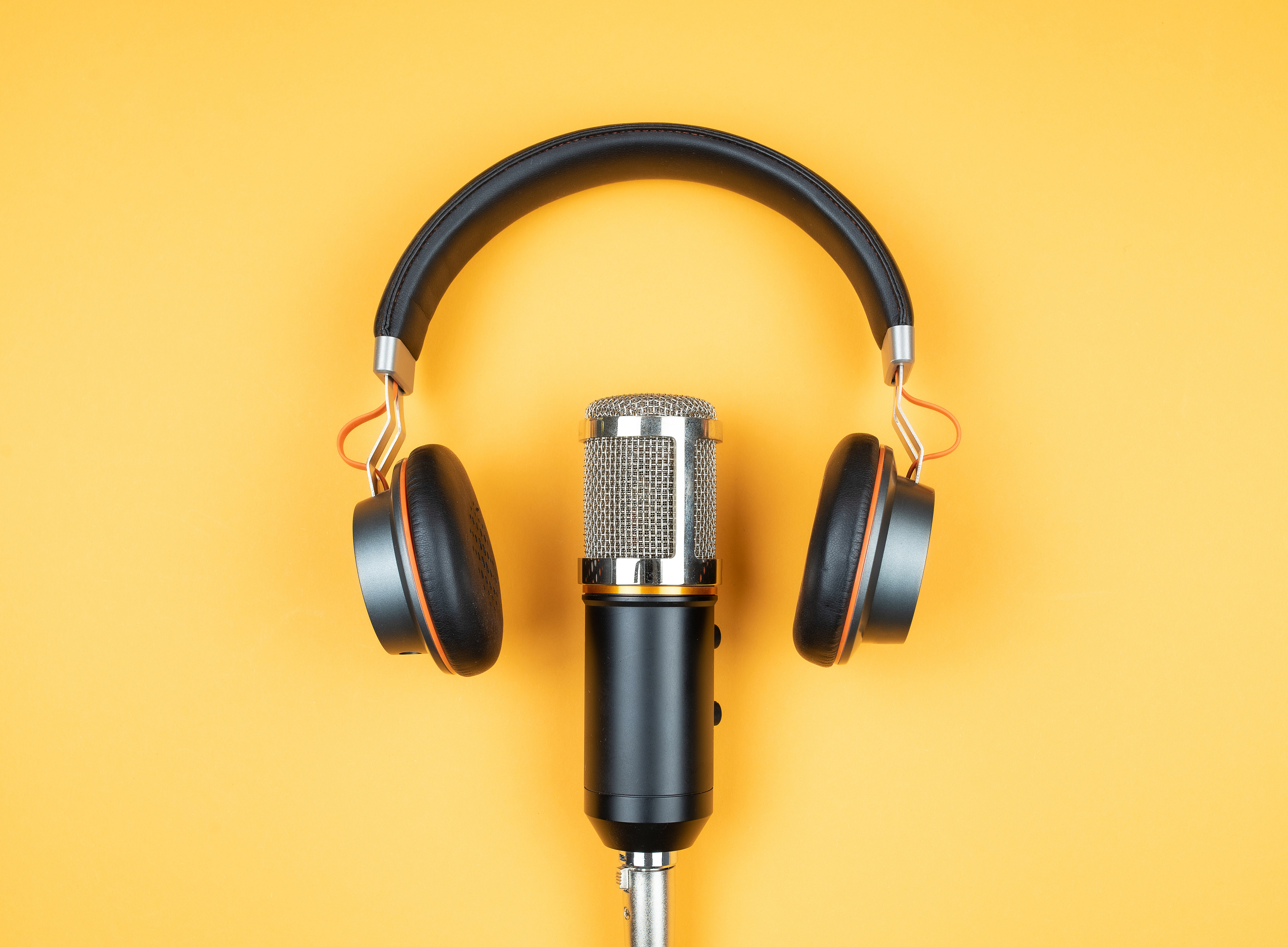 podcasting concept, directly above view of headphones and recording microphone on orange background ©Christian Horz