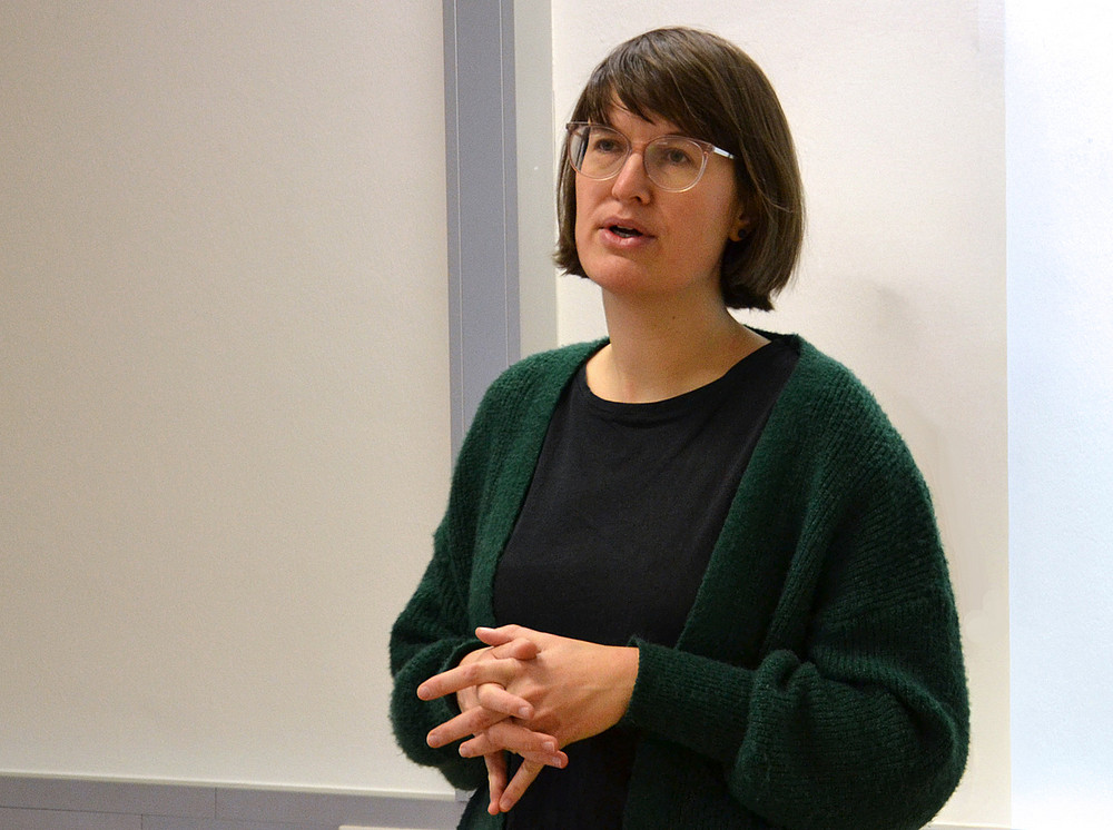 eine Frau mit schulterlangen braunen Haaren und Brille, die vor einer weißen Wand steht und spricht ©Uni Graz/Braunegger