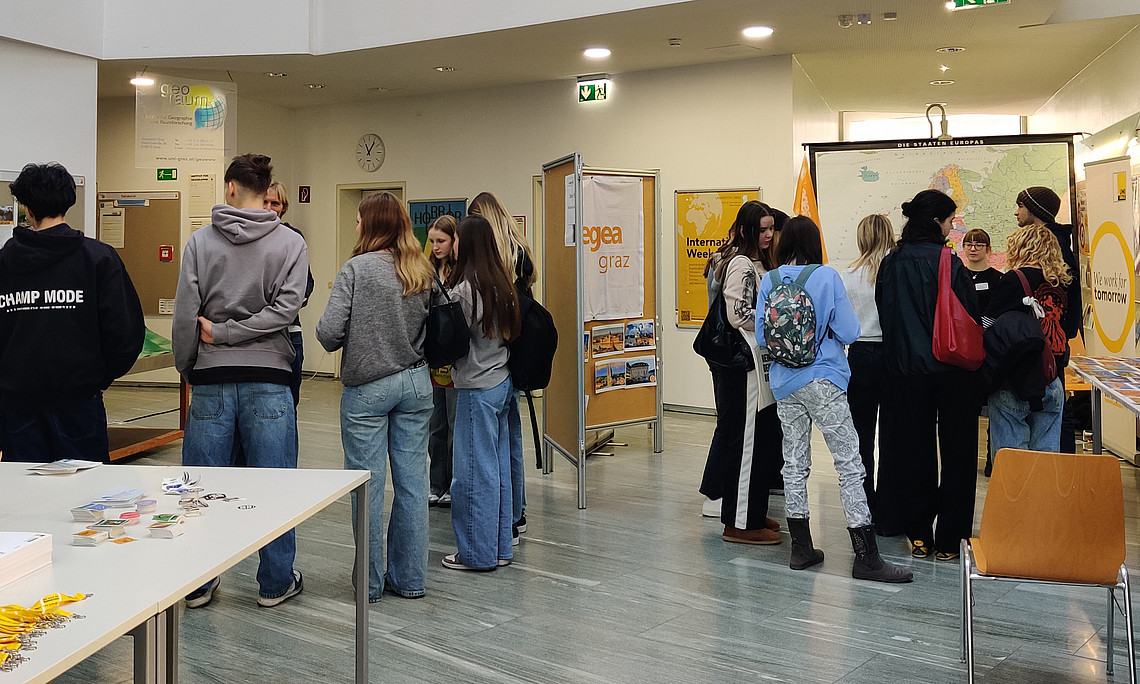 mehrere Gruppen von Schüler:innen stehen in Raum vor verschiedenen Tafeln