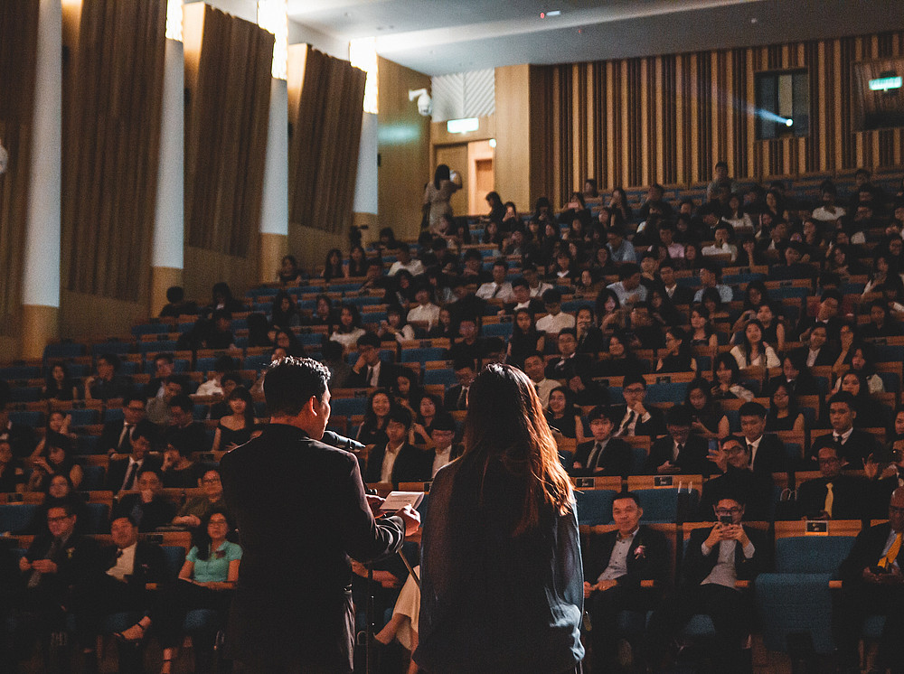 Zwei Personen stehen in einem gefüllten Hörsaal am Podium. ©Wan San Yip - unsplash.com