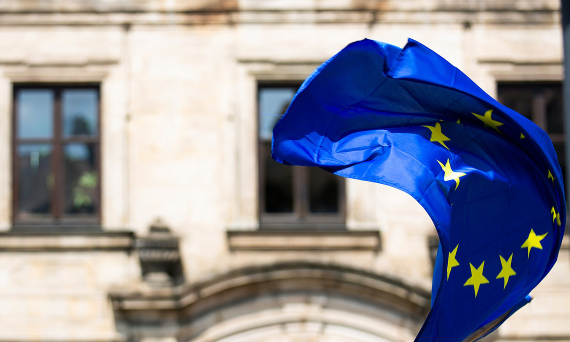 EU-Fahne mit Universitätsgebäude