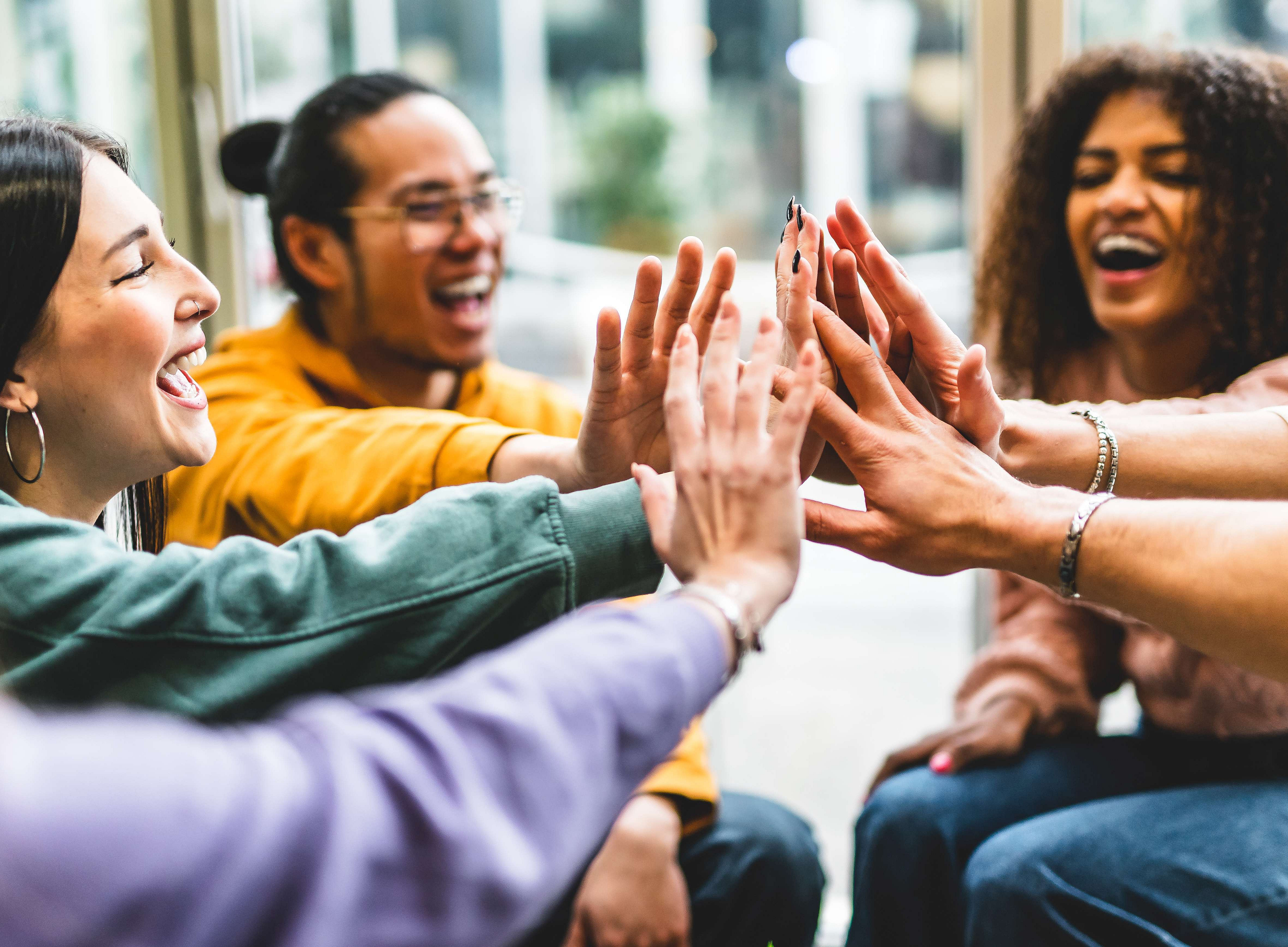 diverse, glückliche junge Studenten schlagen die Hände übereinander – Gruppe diverser Studenten ©Nicolas Micolani - stock.adobe.com