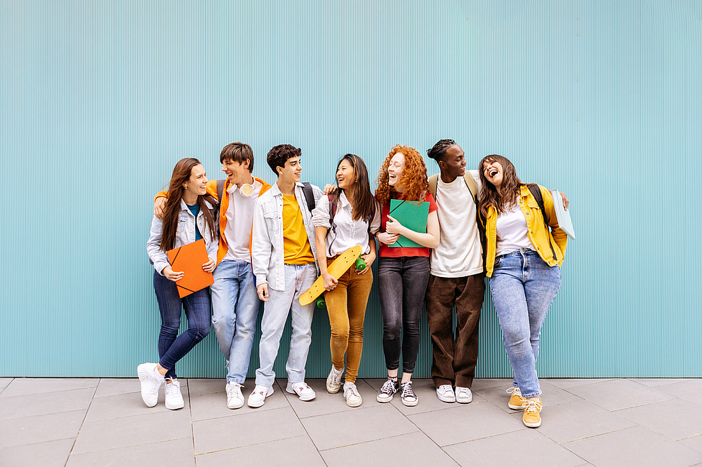 Happy multiracial students standing over isolated blue backgroun Studierende haben Spaß