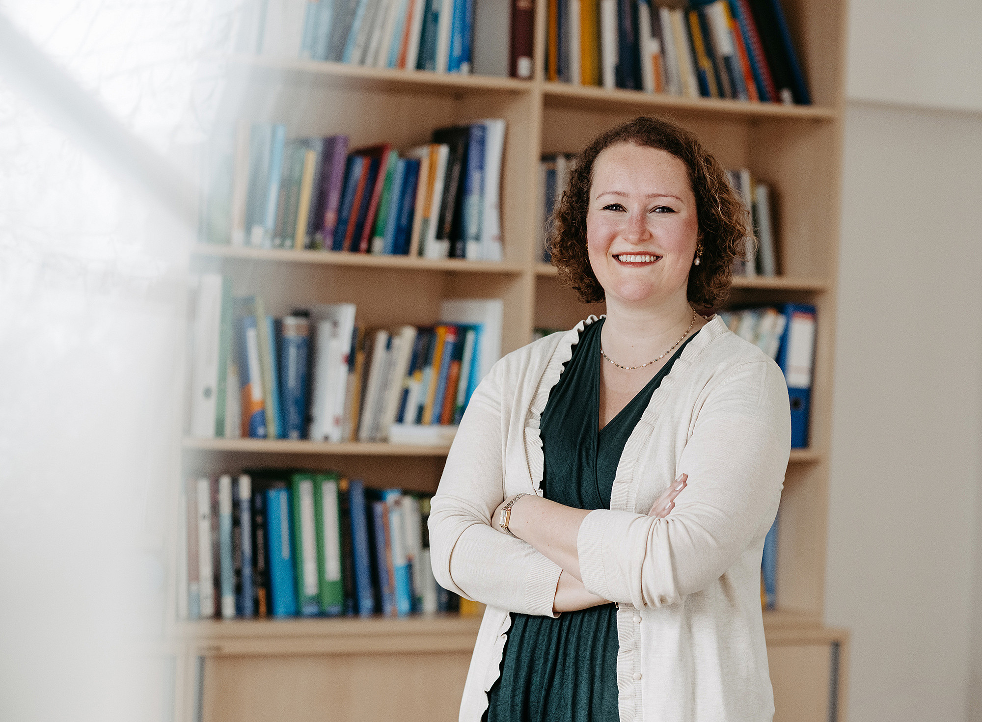 Germanistin Isabella Manago steht mit verschränkten Armen vor einem Bücherregal ©MICHAELA BEGSTEIGER