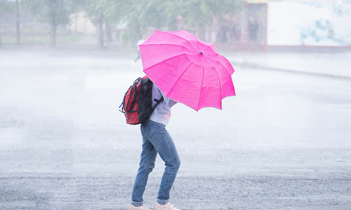 Sturm, starker Regen in der Stadt. Menschen im Regen mit einem Regenschirm.