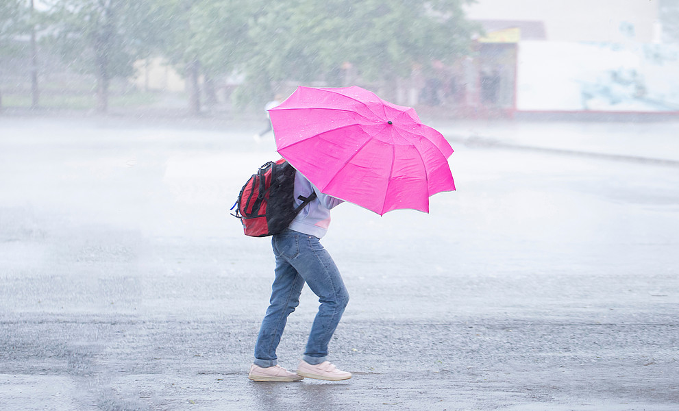 Sturm, starker Regen in der Stadt. Menschen im Regen mit einem Regenschirm.