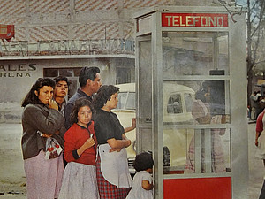 Drei Frauen, zwei Männer und ein Kleinkind stehen vor einer Telefonzelle in der gerade eine Frau telefoniert ©Voces de teléfonos de México, Abril 1963