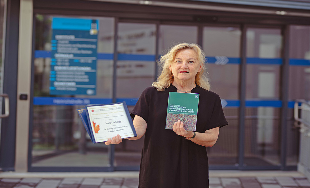 Literaturwissenschaftlerin Maria Löschnigg mit ihrem Buch und der Preisurkunde vor dem Institut für Anglistik
