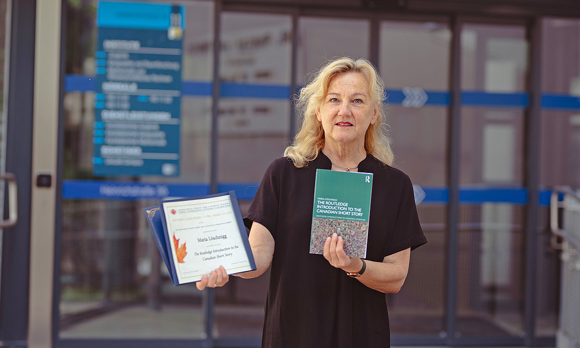 Literary scholar Maria Löschnigg with her book and the award certificate in front of the Department of English Studies