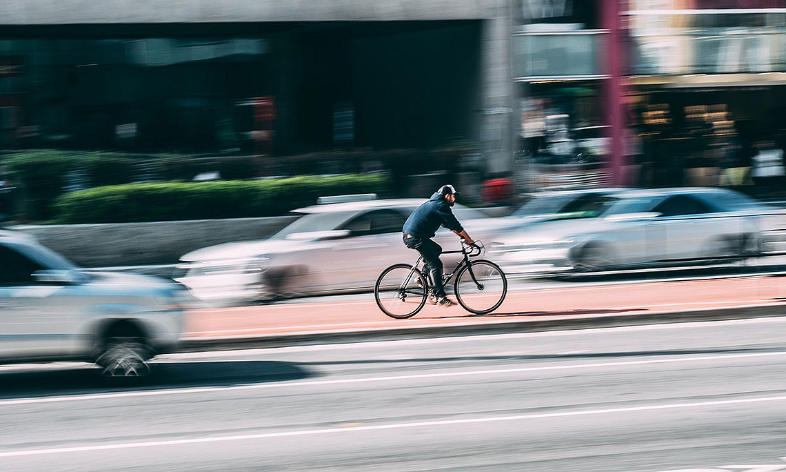 Radfahrer auf Radweg zwischen fahrenden Autos. Foto: pixabay