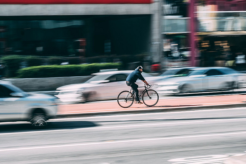 Radfahrer auf Radweg zwischen fahrenden Autos. Foto: pixabay