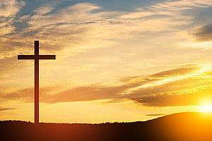 Kreuz auf einem Hügel bei Sonnenuntergang
