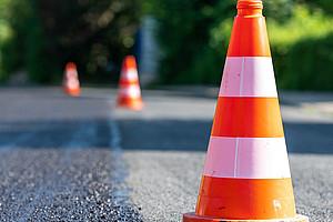 frisch asphaltierte Straße mit rot-weiß-roten Leitkegeln