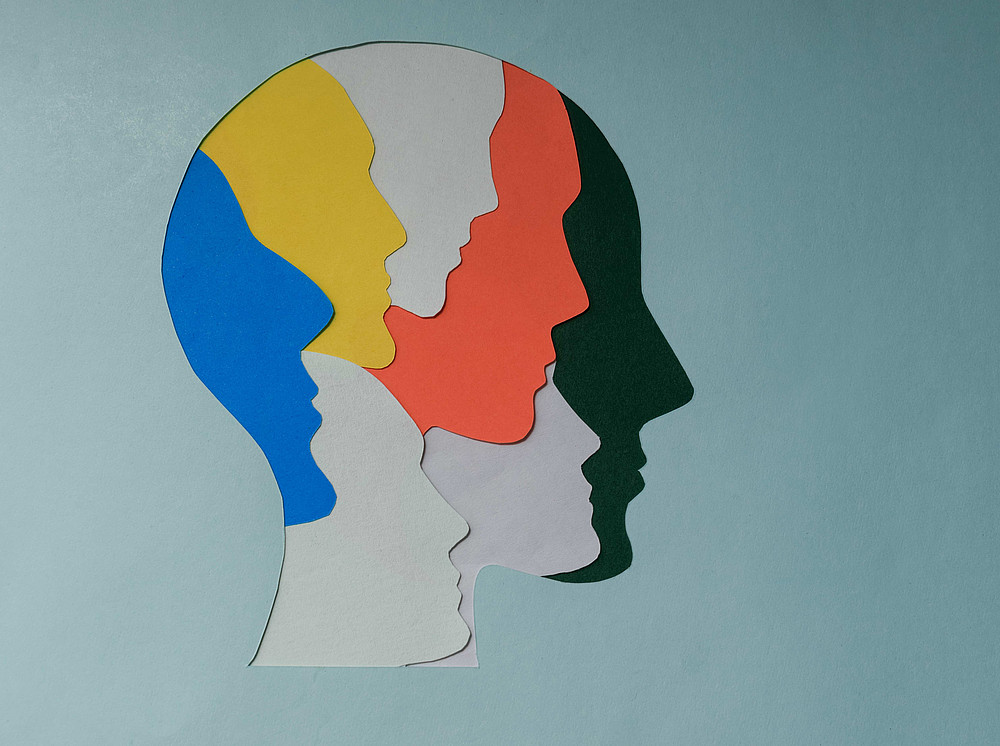 Eine stilisierte Illustration eines menschlichen Kopfes, die aus mehreren übereinanderliegenden, farbigen Profil-Silhouetten besteht. ©Anbu_Creations