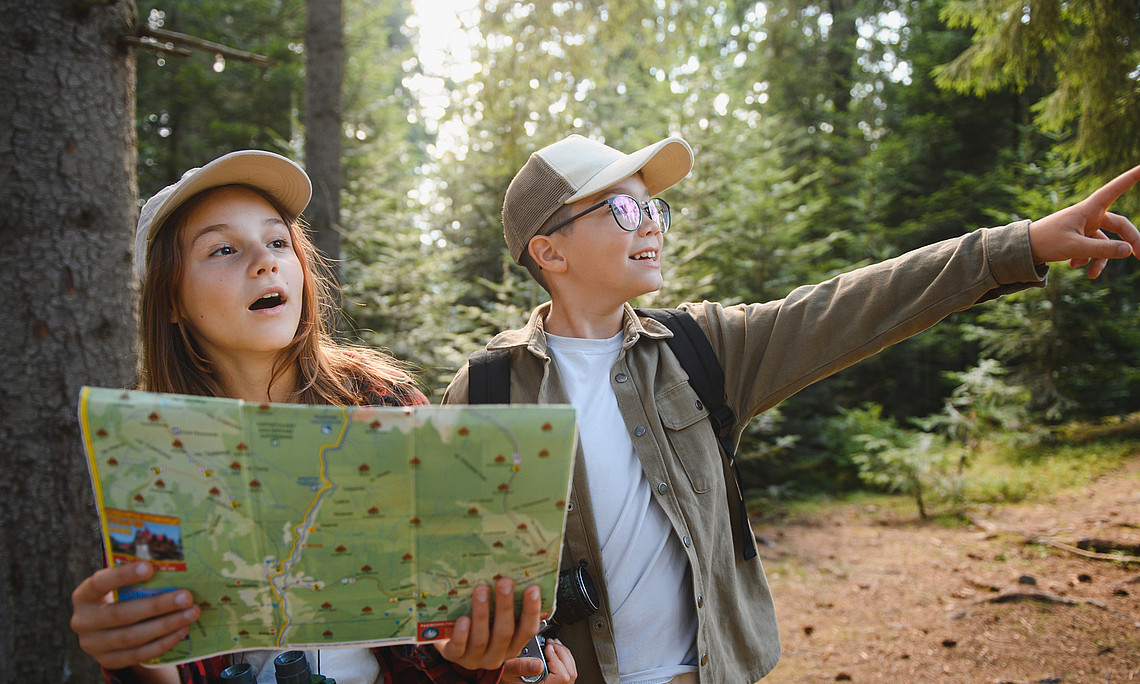 Zwei Kinder mit Landkarte im Wald