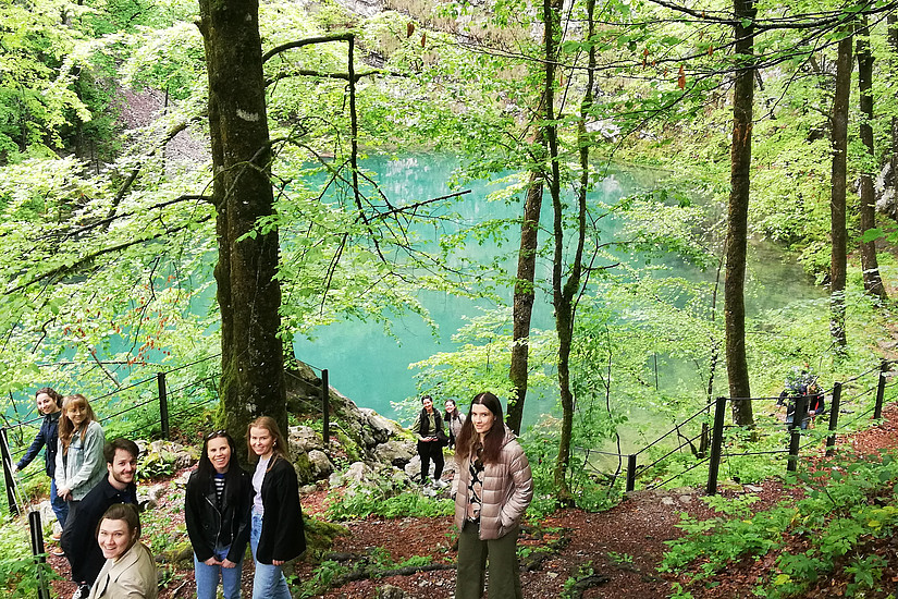 Gruppe spaziert im Wald neben Gewässer