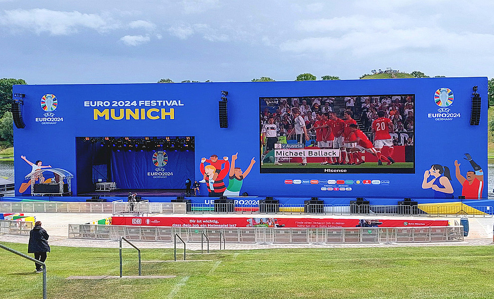 Ein leerer Platz mit einer großen LED-Leinwand, auf der ein Fußballspiel gezeigt wird.